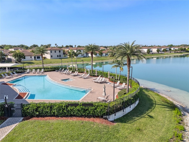 pool featuring fence, a water view, a residential view, a yard, and a patio