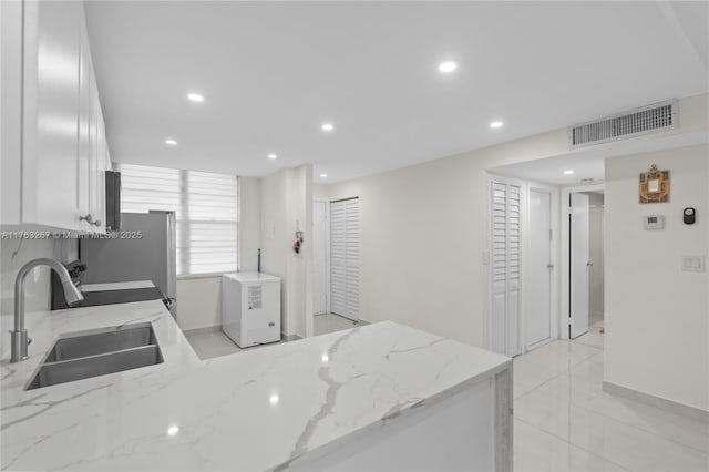 kitchen featuring visible vents, a sink, light stone counters, white cabinetry, and recessed lighting