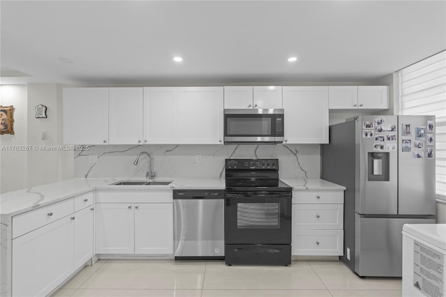 kitchen featuring a sink, appliances with stainless steel finishes, white cabinets, light tile patterned floors, and decorative backsplash