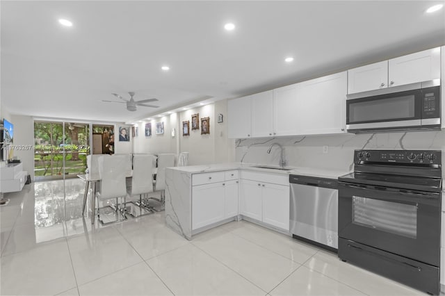 kitchen featuring a sink, stainless steel appliances, tasteful backsplash, and white cabinetry