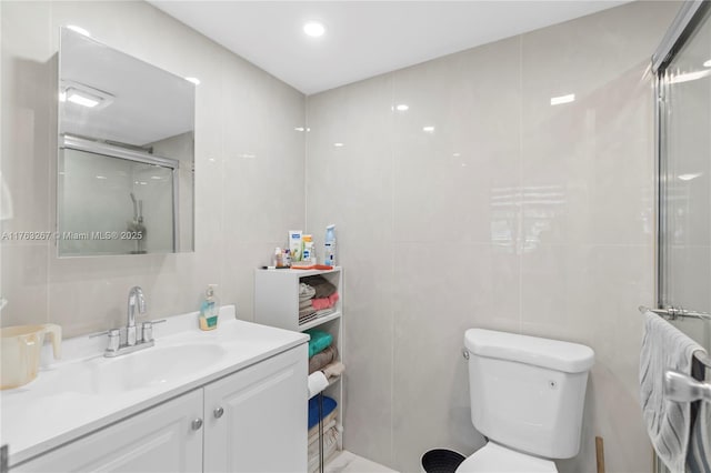 full bath with toilet, a stall shower, tile walls, and vanity