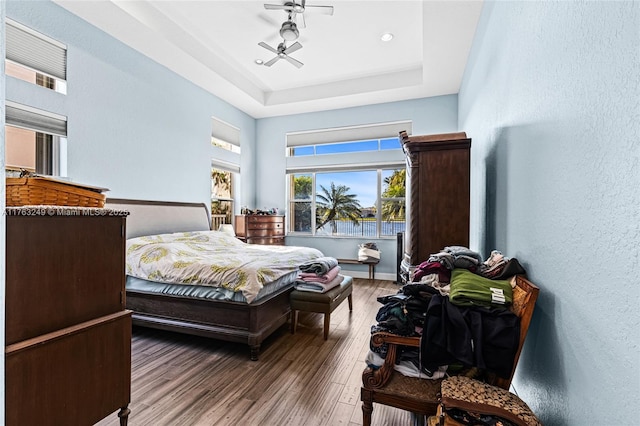 bedroom with a raised ceiling, wood finished floors, and baseboards