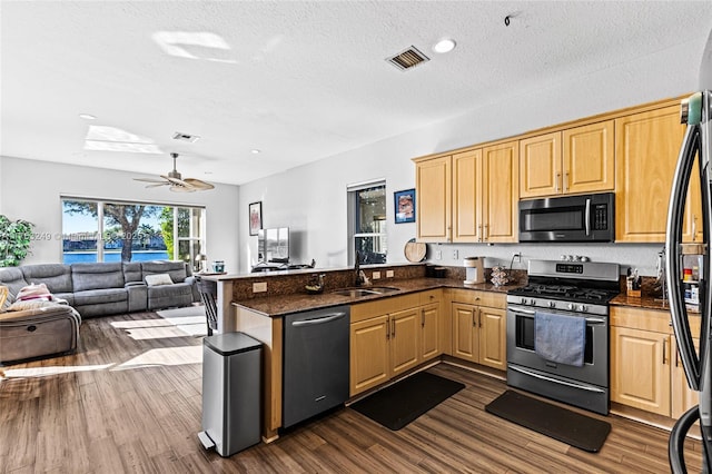 kitchen with visible vents, a sink, open floor plan, appliances with stainless steel finishes, and a peninsula