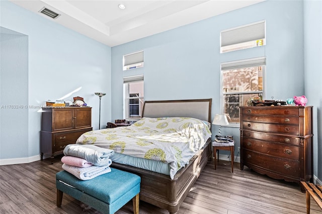 bedroom with visible vents, baseboards, and wood finished floors