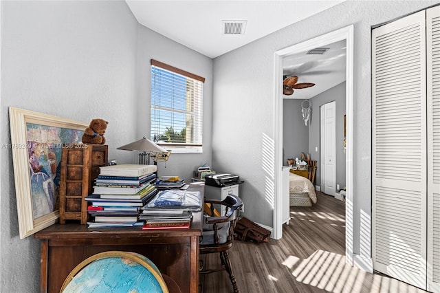 office space with a textured wall, visible vents, baseboards, and wood finished floors