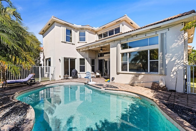 back of house featuring fence, stucco siding, a patio, an outdoor pool, and a ceiling fan