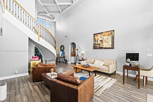 living area with baseboards, stairway, wood finished floors, arched walkways, and coffered ceiling