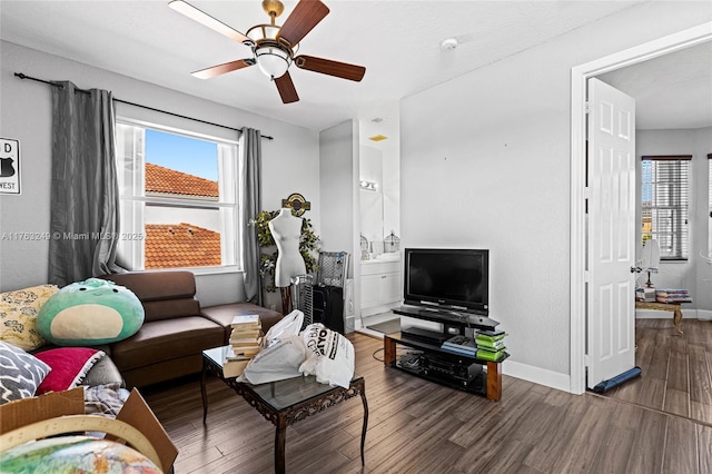 living area featuring plenty of natural light, wood finished floors, baseboards, and ceiling fan