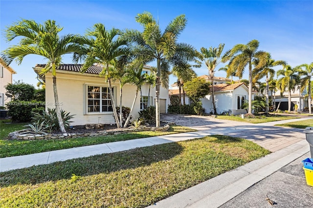 view of front of home with a tiled roof, stucco siding, driveway, and a front lawn