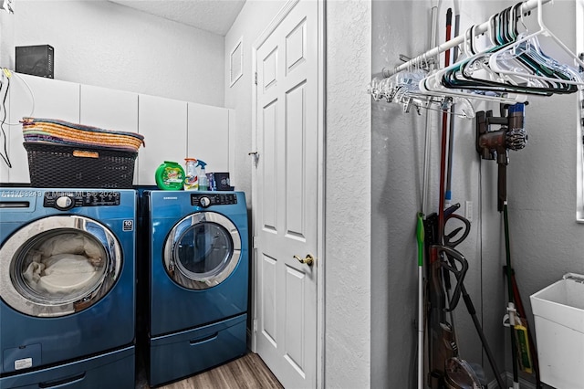 laundry area with wood finished floors, independent washer and dryer, a textured wall, and a sink