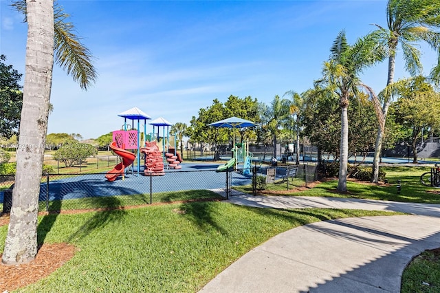 community jungle gym featuring a lawn and fence