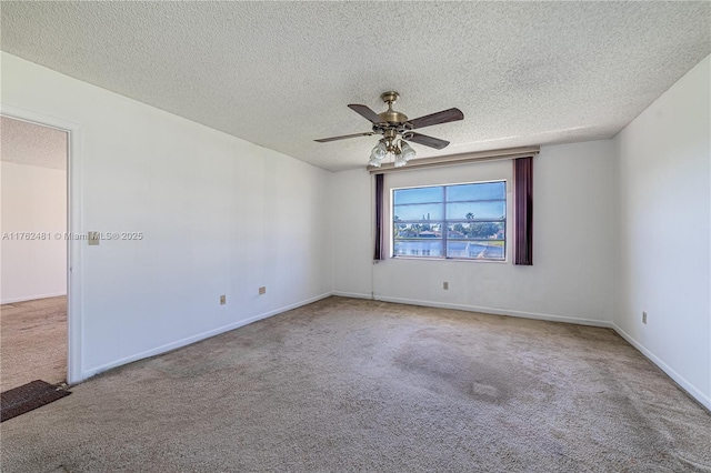 carpeted spare room with a ceiling fan, baseboards, and a textured ceiling