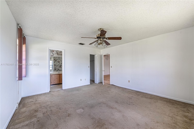 unfurnished bedroom with baseboards, carpet floors, ceiling fan, ensuite bathroom, and a textured ceiling