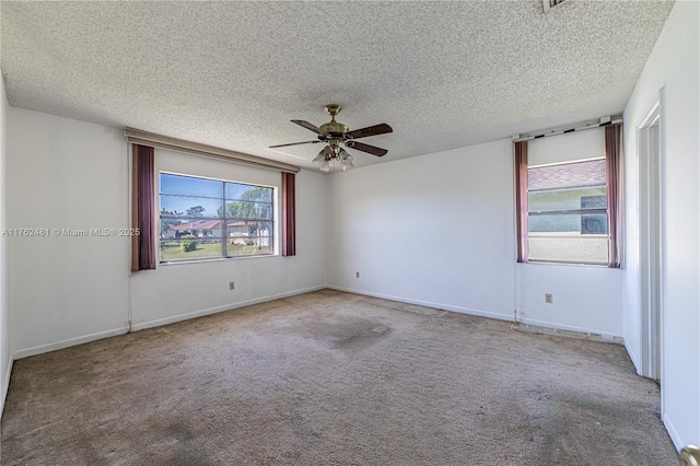 carpeted spare room with a ceiling fan, baseboards, and a textured ceiling