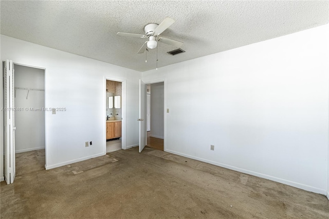 unfurnished bedroom with a spacious closet, visible vents, carpet, a closet, and a textured ceiling