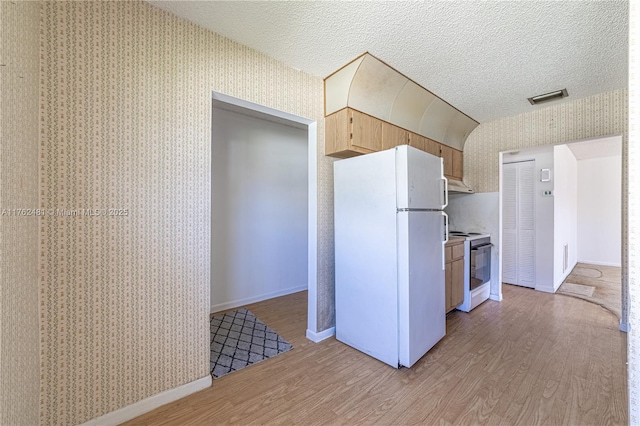 kitchen with a textured ceiling, white appliances, light wood-style floors, and wallpapered walls