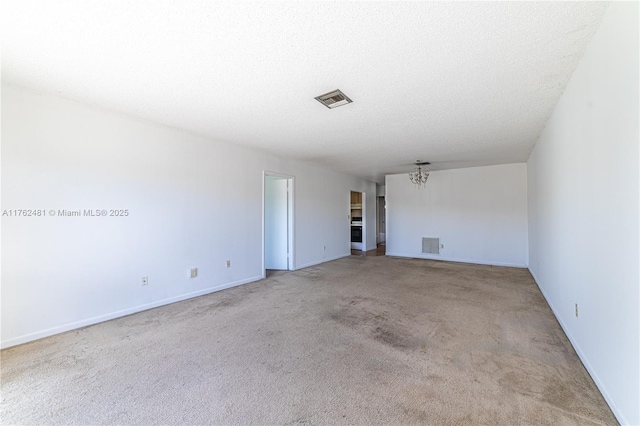 carpeted empty room with visible vents, baseboards, a textured ceiling, and an inviting chandelier