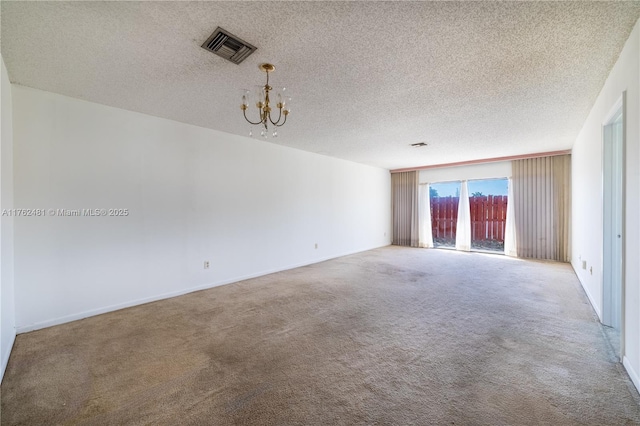 spare room with an inviting chandelier, visible vents, carpet floors, and a textured ceiling