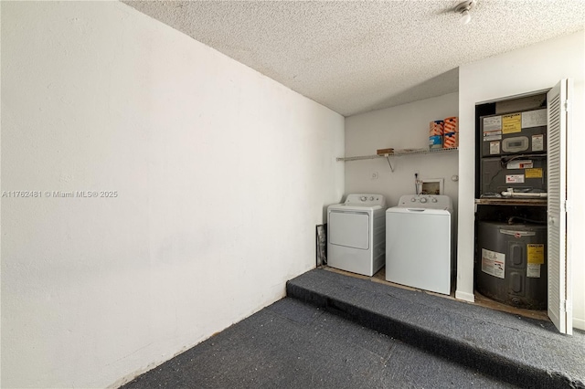 washroom featuring a textured ceiling, water heater, and washing machine and clothes dryer