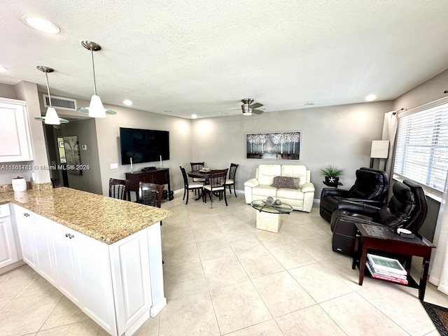 kitchen featuring visible vents, a textured ceiling, open floor plan, white cabinets, and light tile patterned floors