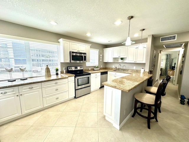 kitchen with visible vents, a breakfast bar, a peninsula, a sink, and stainless steel appliances