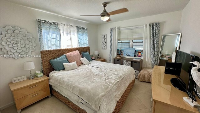 bedroom featuring ceiling fan, light tile patterned floors, and a textured ceiling