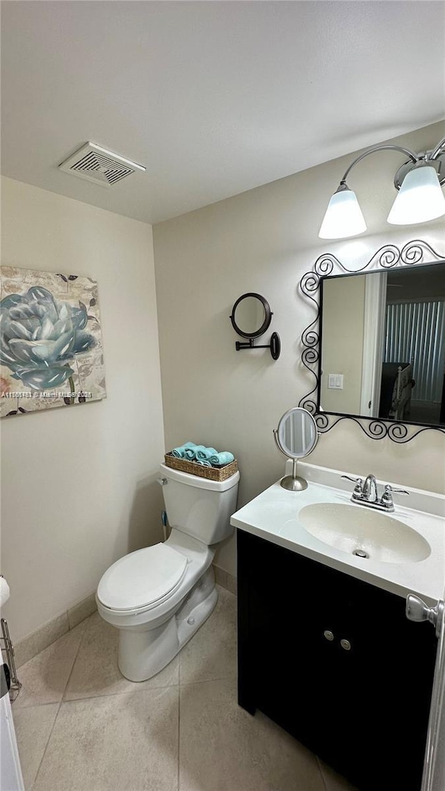 half bathroom with tile patterned flooring, visible vents, baseboards, toilet, and vanity