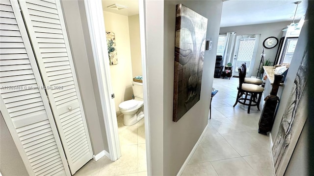 corridor featuring light tile patterned floors, baseboards, and visible vents