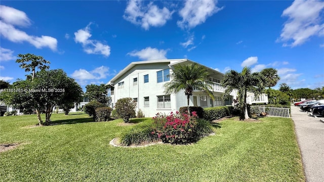 view of property exterior featuring a balcony, stucco siding, and a yard