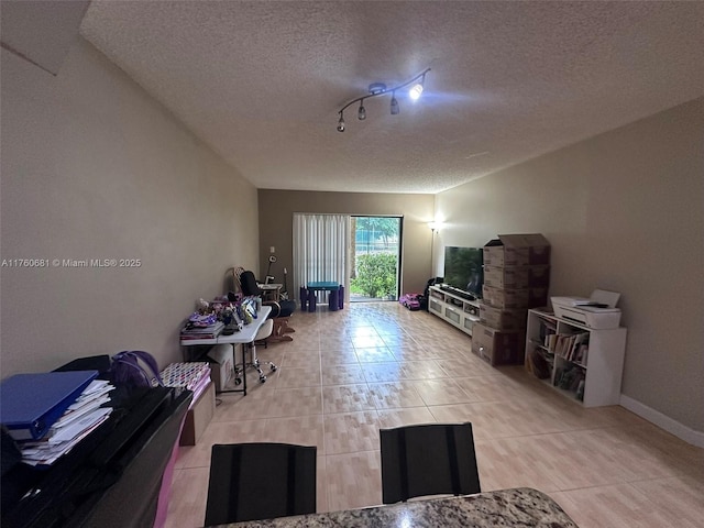 living area with light tile patterned flooring, a textured ceiling, and baseboards