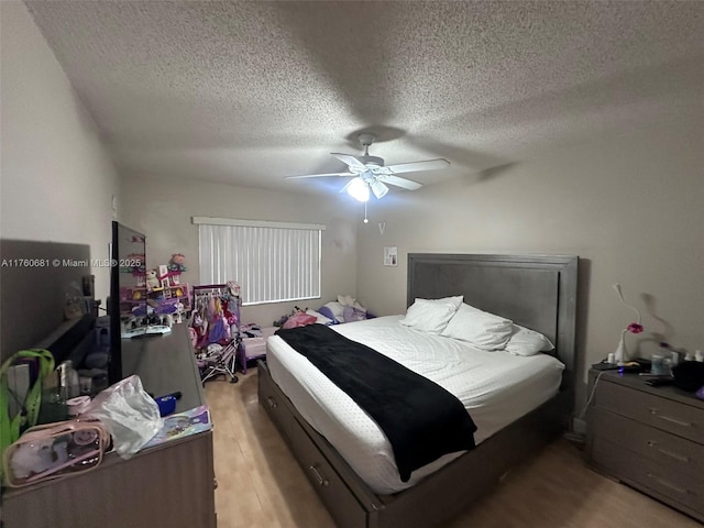 bedroom featuring a textured ceiling, light wood-style flooring, and ceiling fan