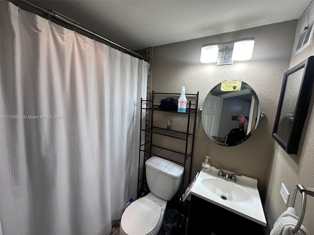 bathroom featuring toilet, curtained shower, a textured ceiling, vanity, and a textured wall