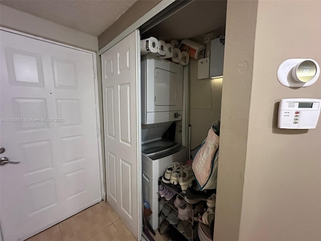 clothes washing area with laundry area, stacked washer / dryer, and light tile patterned floors