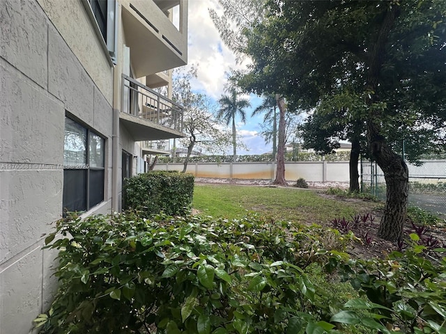 view of yard with a water view, a balcony, and fence