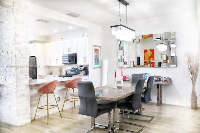 dining area featuring visible vents, light wood-type flooring, and baseboards