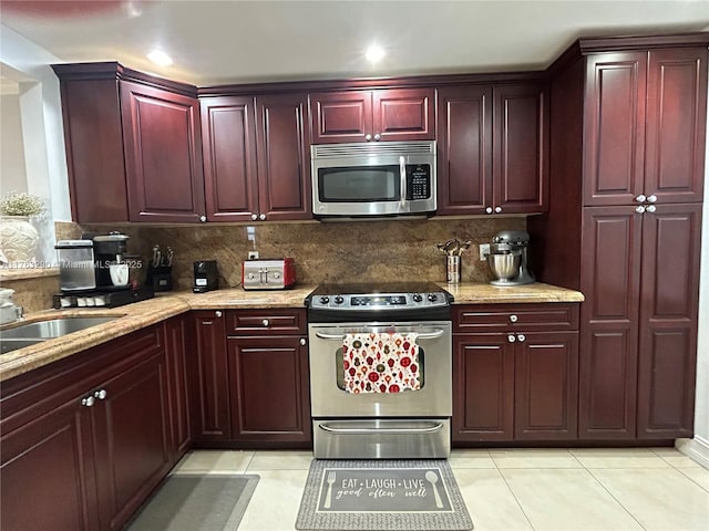 kitchen with dark brown cabinets, light tile patterned flooring, tasteful backsplash, and appliances with stainless steel finishes