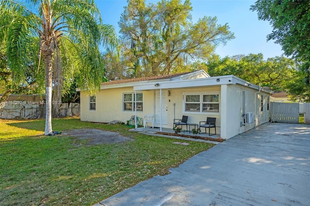 view of front of house with stucco siding, a front yard, and fence