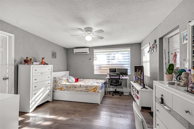 bedroom with hardwood / wood-style floors, a textured wall, a wall mounted air conditioner, and a ceiling fan