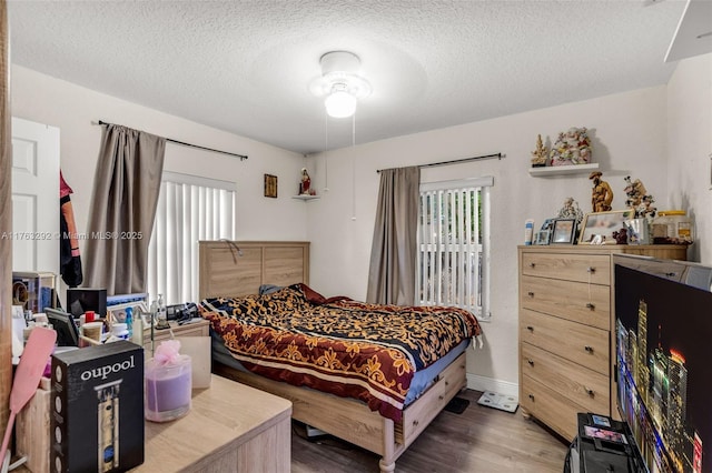 bedroom with a textured ceiling, baseboards, and wood finished floors