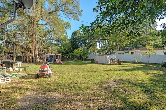 view of yard featuring a fenced backyard, a storage unit, a playground, and an outdoor structure