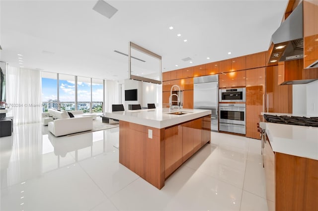 kitchen featuring open floor plan, appliances with stainless steel finishes, brown cabinetry, modern cabinets, and a sink