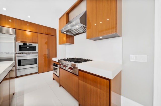 kitchen featuring wall chimney range hood, a warming drawer, modern cabinets, and appliances with stainless steel finishes