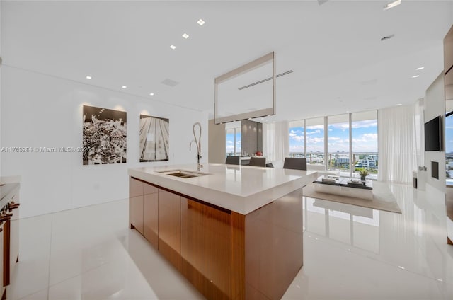 kitchen with modern cabinets, a sink, light countertops, a wall of windows, and light tile patterned floors