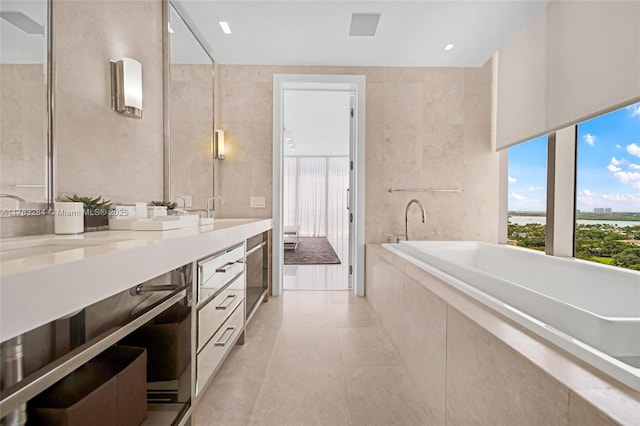 full bathroom featuring tile patterned floors, tile walls, tiled tub, and double vanity