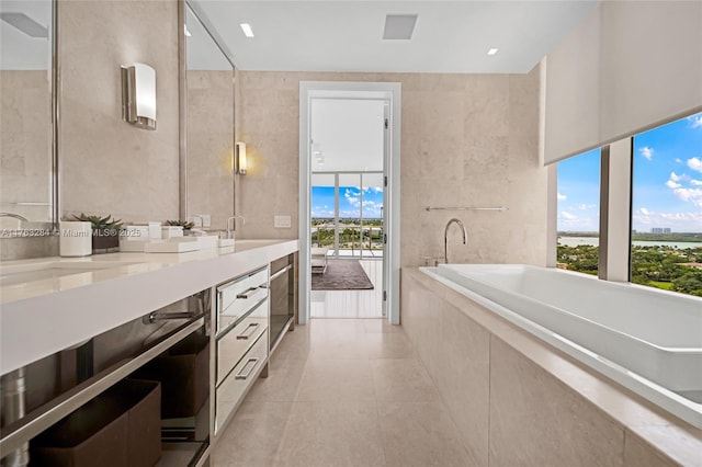 full bath with tiled bath, tile walls, double vanity, and tile patterned flooring