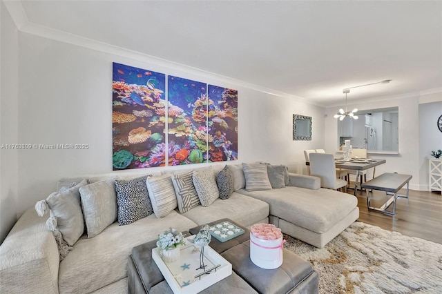 living area with wood finished floors, a notable chandelier, and ornamental molding