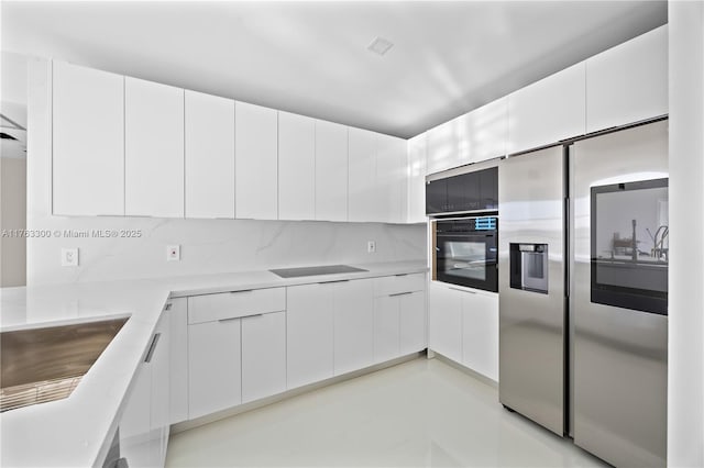 kitchen with modern cabinets, black appliances, white cabinets, light countertops, and decorative backsplash