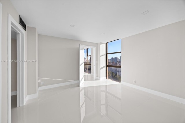 spare room featuring baseboards and expansive windows