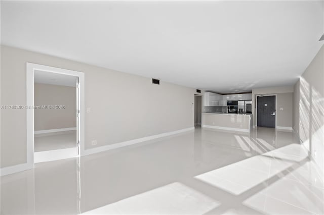 unfurnished living room with light tile patterned floors, visible vents, and baseboards