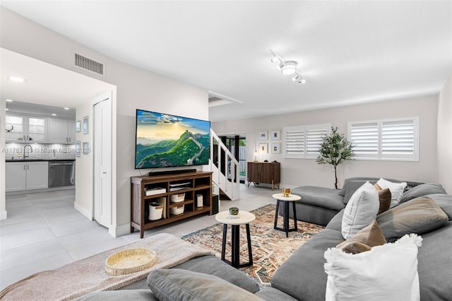 living area with light tile patterned floors, visible vents, stairway, and a wealth of natural light